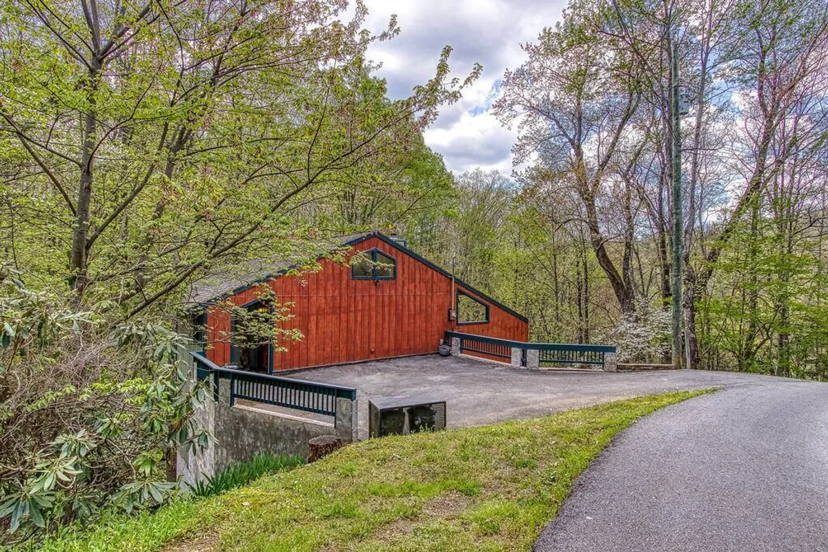This exterior image showcases the wooden facade of the cabin surrounded by lush greenery, with a welcoming patio that hints at quiet relaxation and immersion in nature. The setting evokes a strong sense of seclusion and tranquility, ideal for couples seeking intimacy and peace.